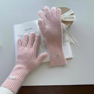 Blush pink ribbed knit touchscreen gloves with a small silver logo detail.