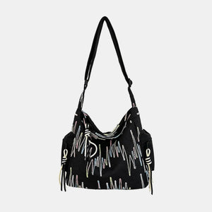 Black slouchy shoulder bag with colorful embroidered abstract pattern and tassel detail.