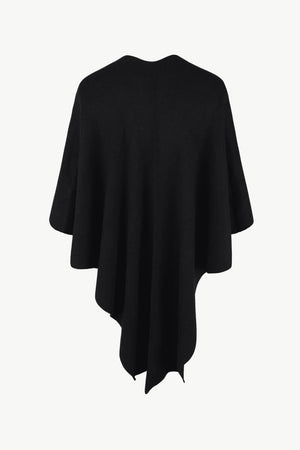 Black knit cape with draped asymmetrical hem and subtle fur trim detail.