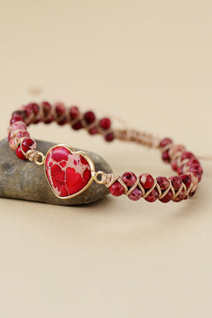 Red heart stone braided bracelet with beaded band and gold accent.