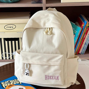 Off-white nylon backpack with drawstring closure, front pocket, side pockets, and panda charm.