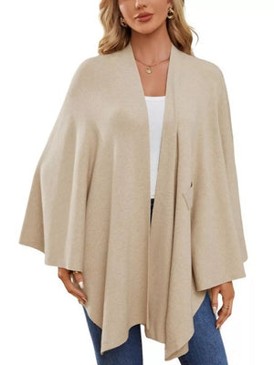Beige knit cape top with draped elegance and tie front detail.