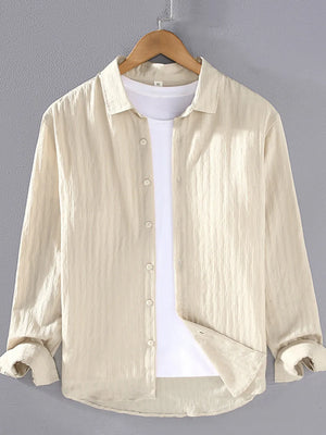 Textured long sleeve button-up shirt in apricot with classic collar, worn over a white t-shirt.