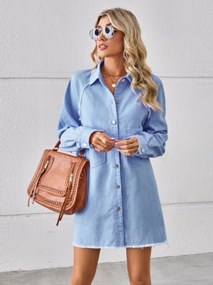 Light blue denim shirt dress with raw hem and button front, styled with a brown crossbody bag.