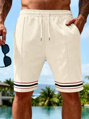 Textured knit drawstring shorts in apricot with striped cuffs and pockets.