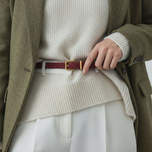 Chic cowhide leather belt in burgundy with gold buckle, worn casually.