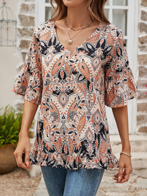 Paisley print v-neck blouse with ruffle hem and bell sleeves in burgundy and tangerine tones.