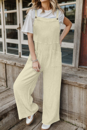 Cream textured cotton overalls with square pockets and wide legs.