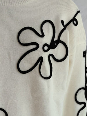 Beige knit sweater with black floral outline embroidery, crew neck, long sleeves.