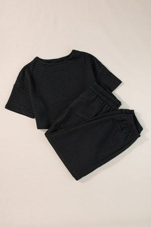 Black quilted knit crop top and jogger set with crew neck and short sleeves.