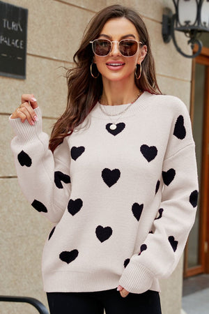 Beige knit sweater with black heart pattern, crew neck, and balloon sleeves.