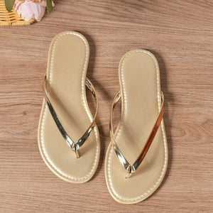 Gold minimalist toe-post sandals with metallic straps.