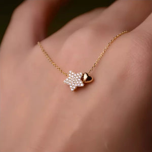Gold necklace with a pave crystal star and a small gold heart charm.
