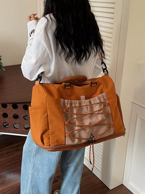 Large orange nylon duffel bag with bungee cord detail and tan accents