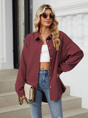 Burgundy corduroy oversized shirt jacket with button front and collar, styled with jeans.