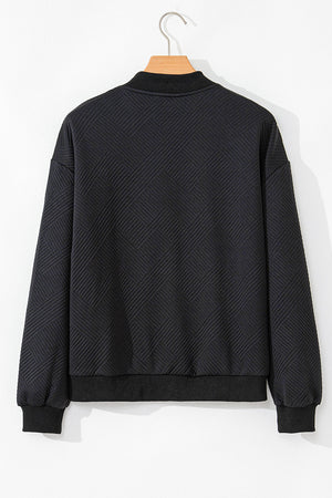 Black bomber jacket with textured diamond quilting and ribbed collar, cuffs, and hem.