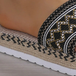 Embroidered espadrille platform slides in black with gold and white geometric pattern.