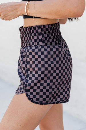 Elastic waist checkerboard running shorts in plaid with a relaxed fit and curved hem.