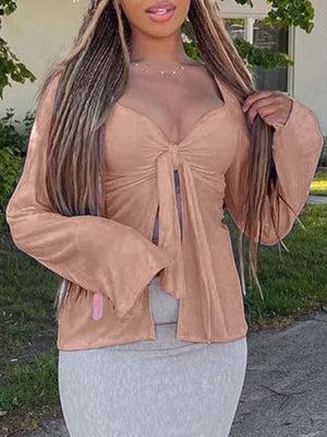 Tie-front long sleeve blouse in pink with a deep V-neck and flared sleeves.