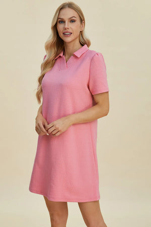 Pink textured V-neck short sleeve mini dress with geometric pattern detail.