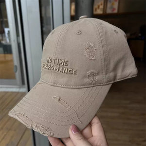 Khaki distressed cotton baseball cap with embroidered "NO TIME FOR ROMANCE" text.