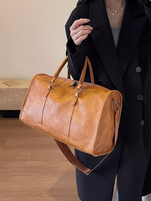 Cognac vintage leather duffle bag with top handles and detachable shoulder strap.