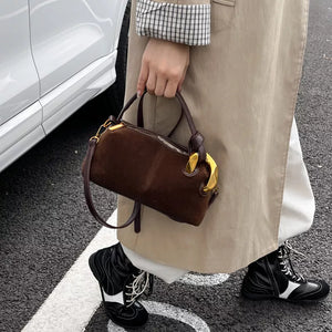 Brown suede crossbody bag with gold hardware and top handles.