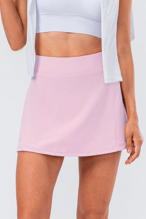 Blush pink performance skort with a pleated skirt and pocket detail.
