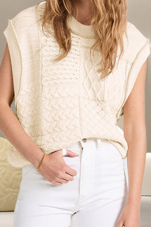 Ivory knit patchwork vest with cable and diamond patterns, mock neck, sleeveless.