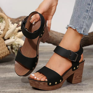 Black platform block heel ankle strap sandals with wood-look sole and gold stud details.