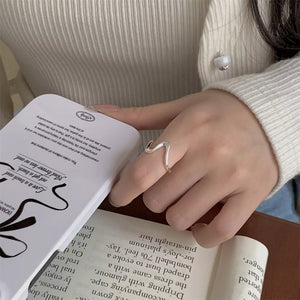 Sterling silver ring with a wavy minimalist design on a woman's finger.