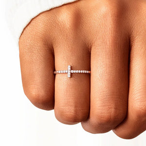 Rose gold pavé cross ring with small stones on a finger