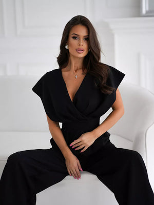 Black surplice wide-leg romper with deep V-neck and cap sleeves.