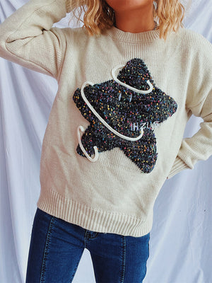 Beige knit jumper with embroidered starburst detail and white piping.