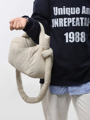 Padded knot shoulder bag in beige with a knotted strap detail.