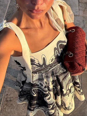 Floral tie-strap mini dress with black and white abstract print and pockets.