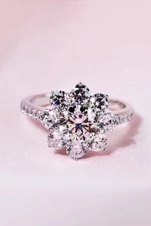 Silver moissanite engagement ring with a petal cluster design and pavé band.