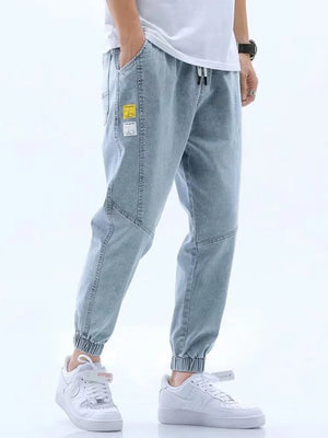 Light blue relaxed fit drawstring jeans with elastic cuffs and patch details.