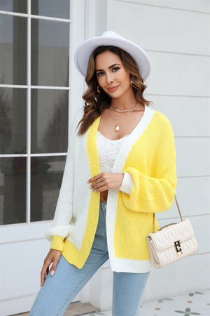 Colorblock knit cardigan with contrast trim in yellow and white acrylic, featuring balloon sleeves and a relaxed fit.