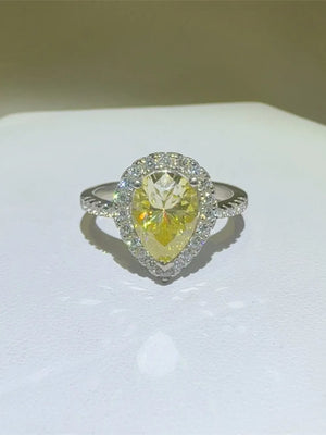 Yellow pear-cut moissanite ring with diamond halo and textured band.