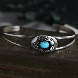 Turquoise cuff bracelet with oval center stone and decorative metalwork