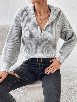 Gray ribbed zip-up sweater with a high collar and balloon sleeves.