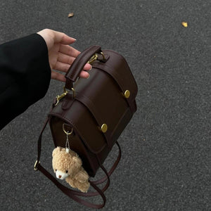 Mini brown pu leather backpack with decorative straps and teddy bear charm.