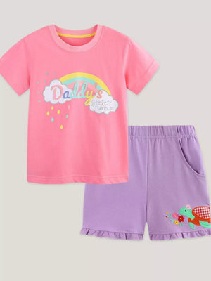 Pink cotton tee with rainbow cloud graphic and purple ruffle shorts with turtle embroidery.