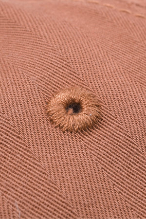 Coral baseball cap with herringbone texture and embroidered eyelet detail