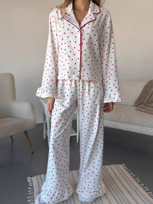 White cotton pajama set with red heart pattern, button front, and ruffled cuffs and hems.