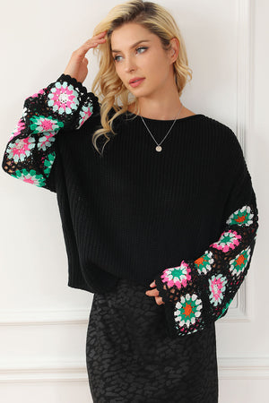 Black knit pullover sweater with crochet granny square sleeves in pink, green, and white.