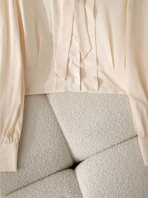 Apricot bow tie blouse with button front and long sleeves.