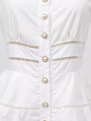 White eyelet midi dress with pearl button detail and cutout waist.
