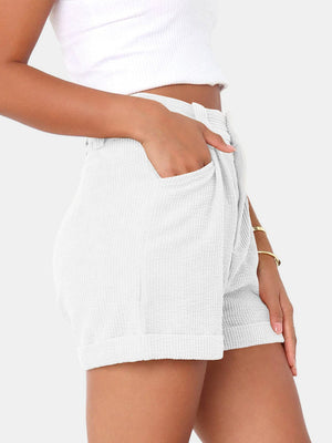 White corduroy pleated high-waist shorts with cuffed hem and pockets.